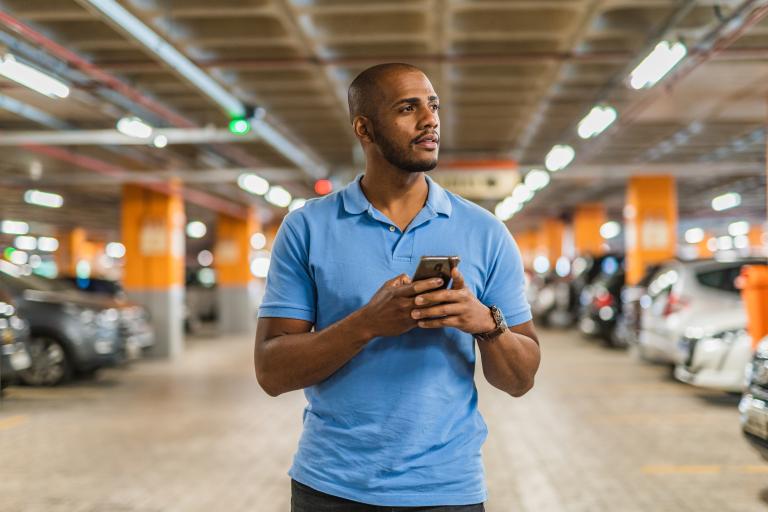 Man in parkeergarage met smartphone