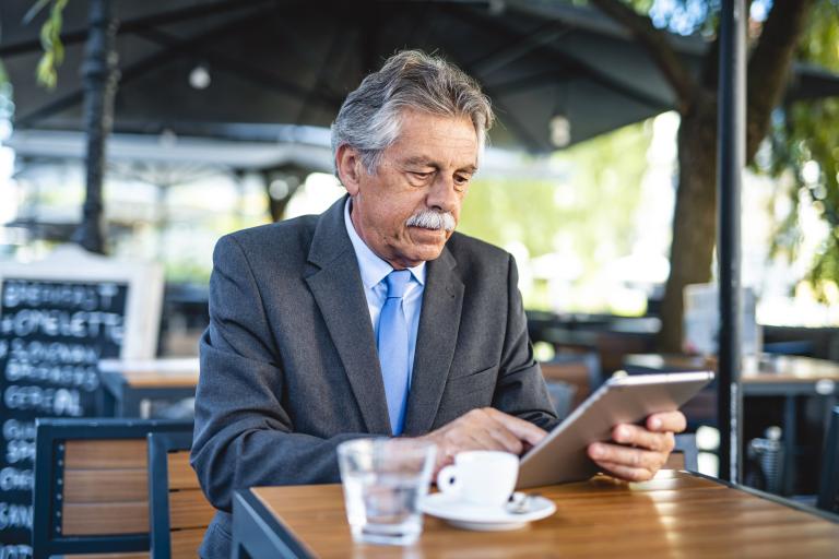 Oudere man op terras met tablet