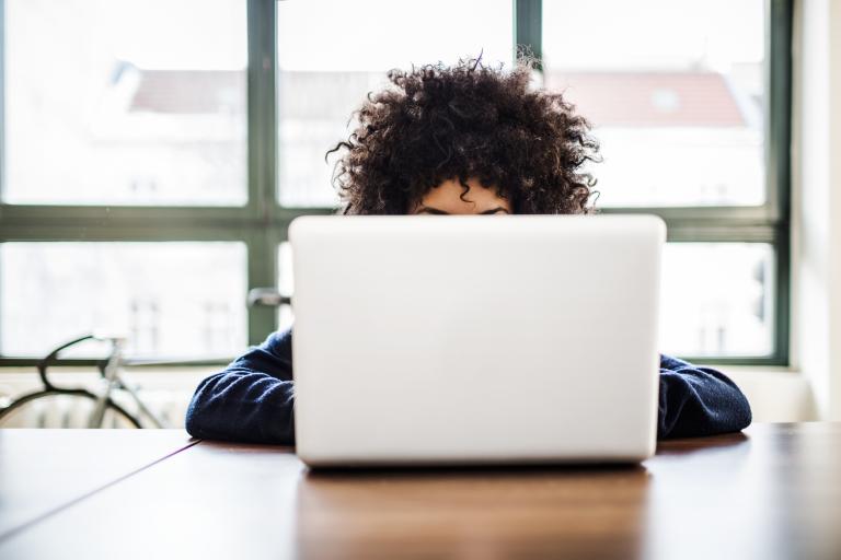 Vrouw met krullen achter laptop