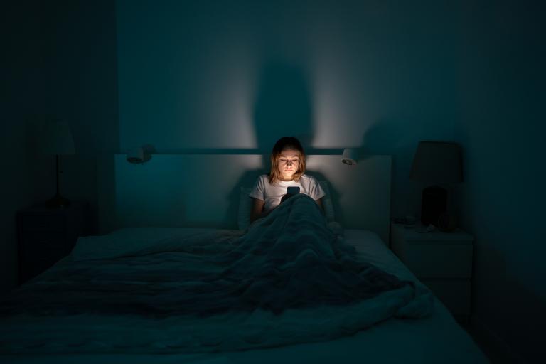 Vrouw in donkere slaapkamer op telefoon