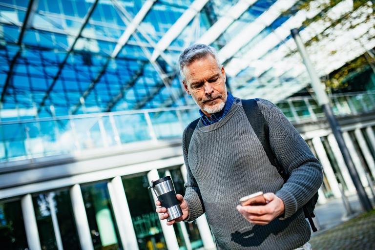 Man loopt buiten en kijkt op telefoon