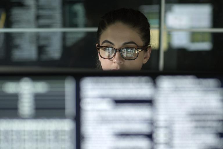 Vrouw met bril achter schermen met computercode