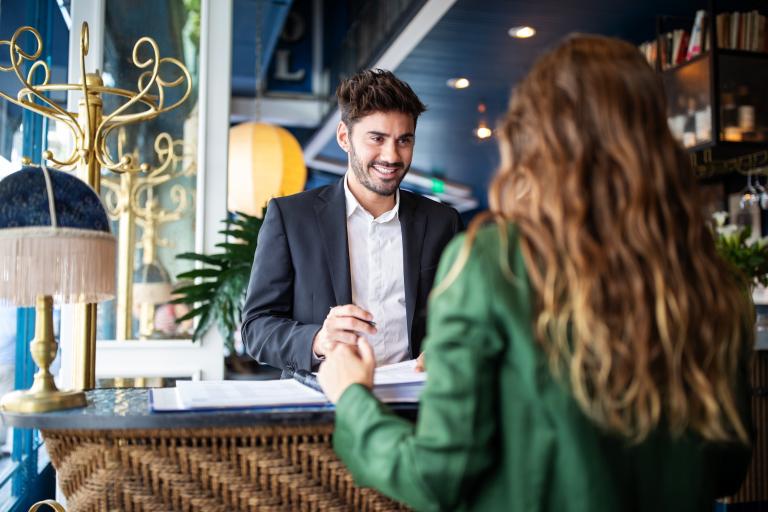 Receptionist checkt gast in bij balie hotel