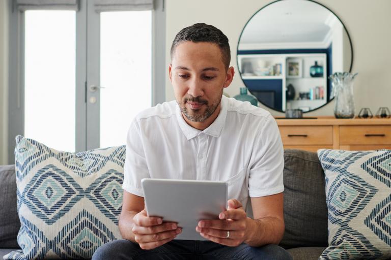 Man op de bank in woonkamer met tablet