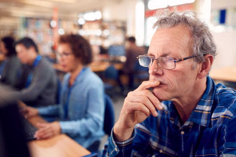 Man in computerzaal kijkt op scherm