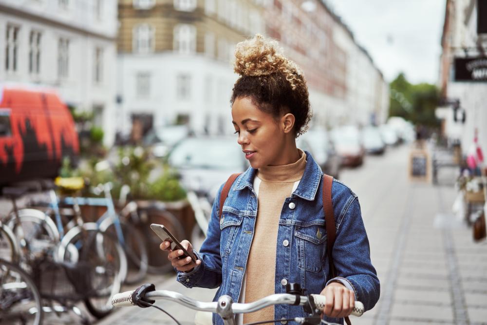 Vrouw buiten met fiets en smartphone