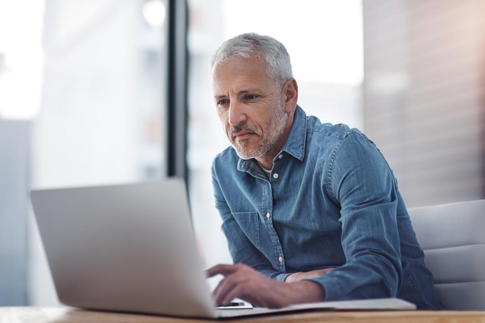 Man aan tafel achter laptop